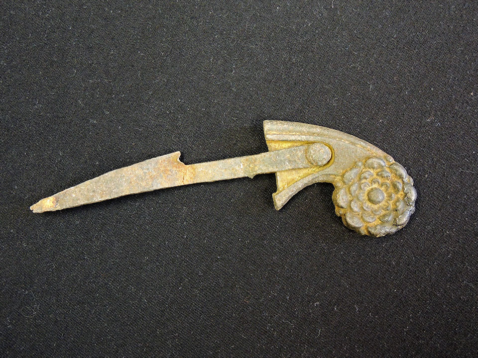 long, metal object with decorative circle on one end and a point at the other