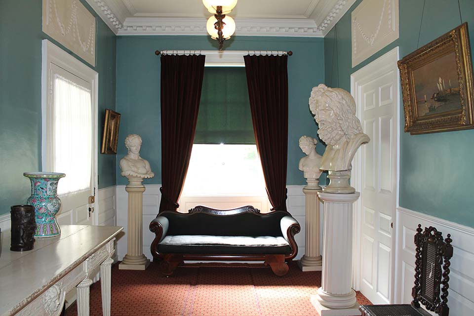 Two men seated in front of a large window, surrounded by statuary.