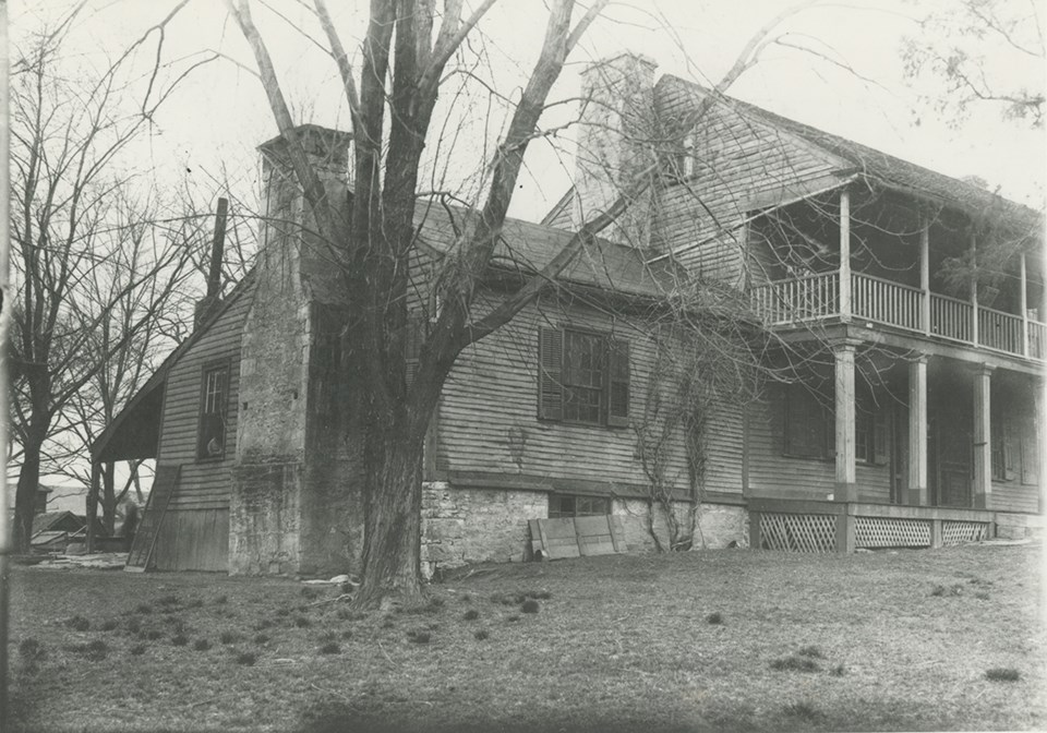 Black and white historic photo of a frame house with large stone chimneys