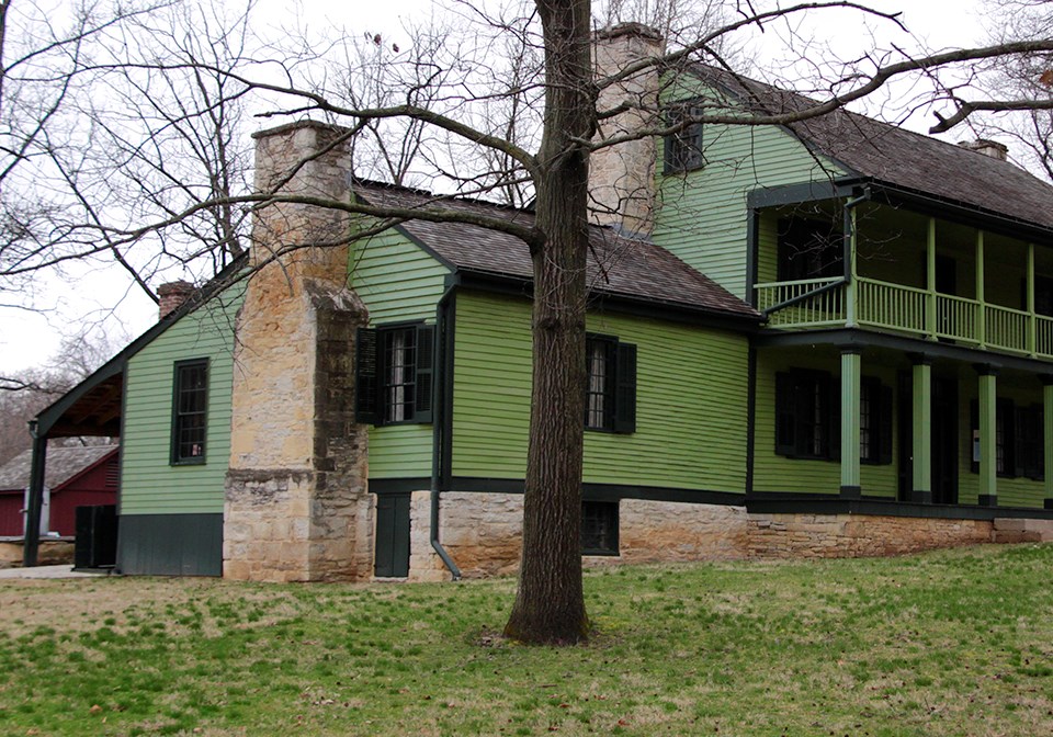 Black and white historic photo of a frame house with large stone chimneys