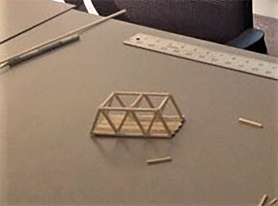 teenage boy building model bridge with popsicle sticks