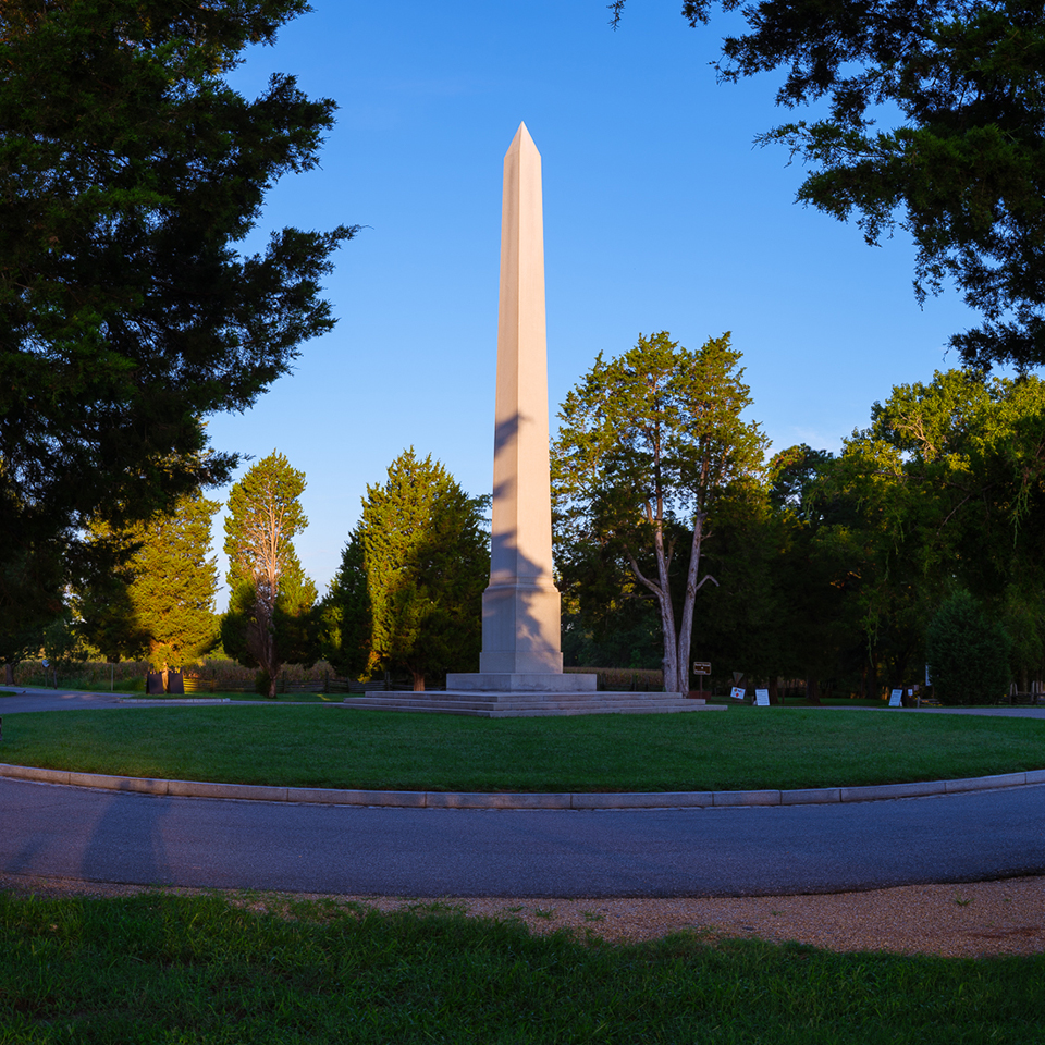 monument being lowered to greased logs by a pulley system attached to wooden derrick