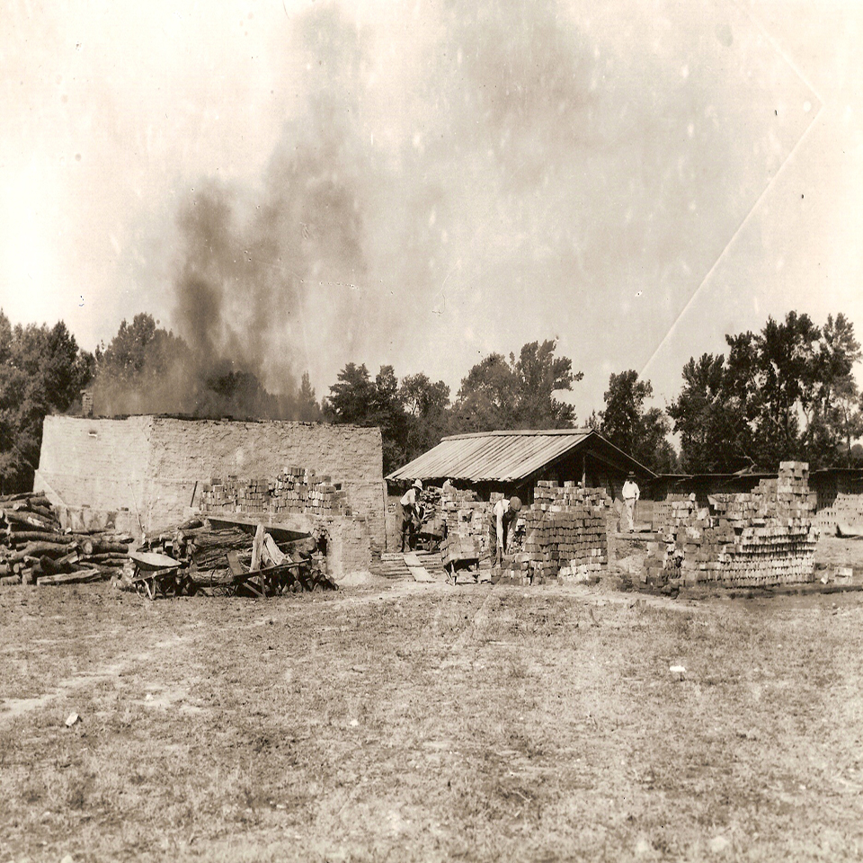 smoking square kiln with bricks stacked nearby