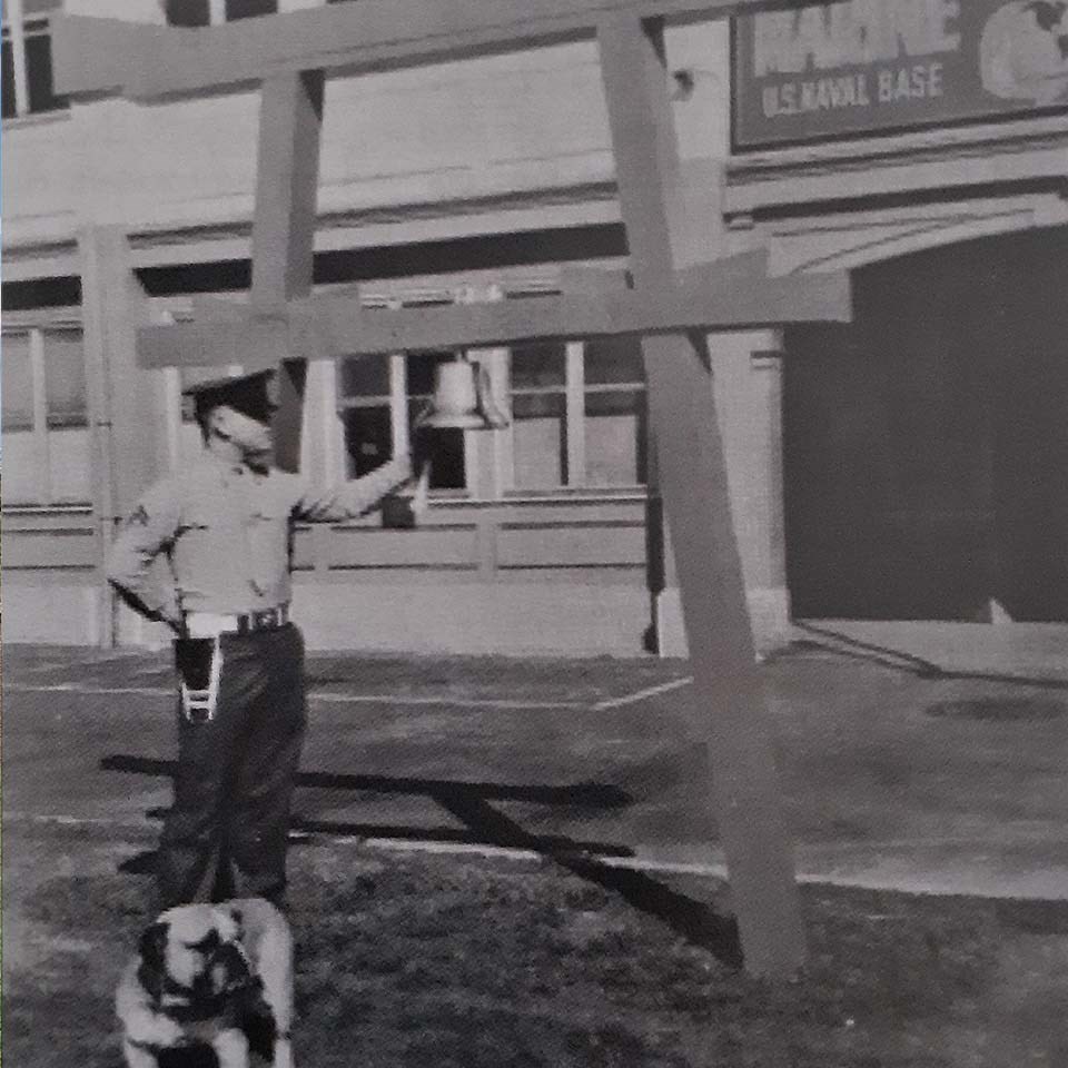 Image of Marine ringing bell on red Shinto torii gate, accompanied by a dog