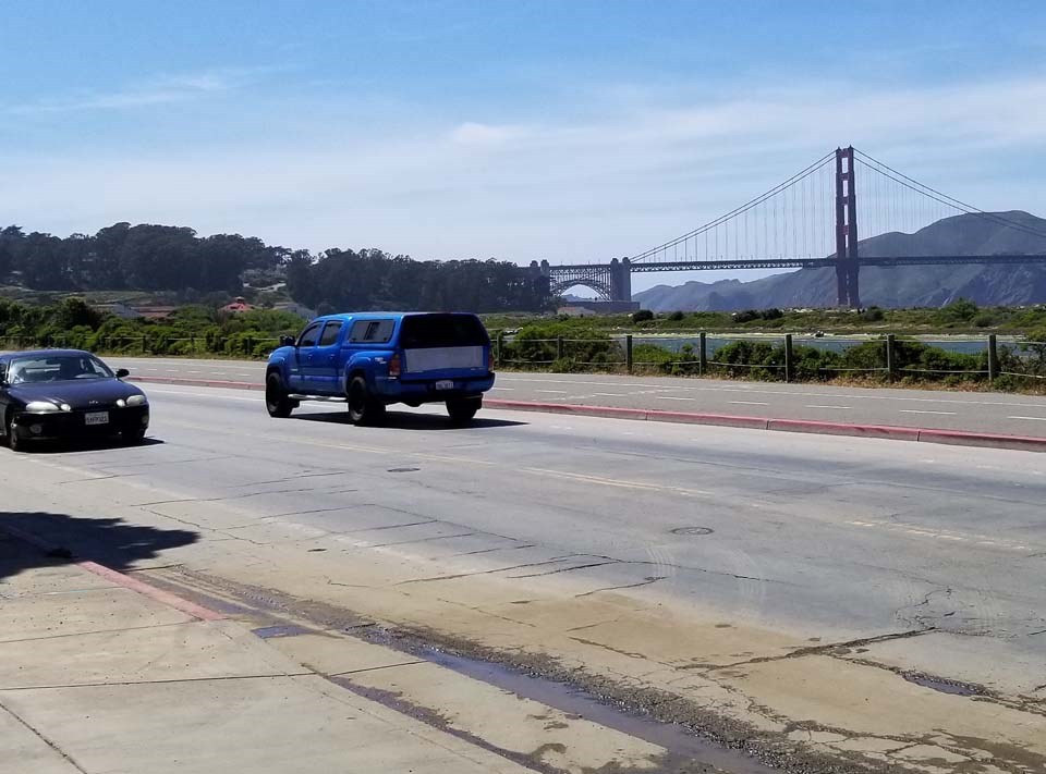 cars on the street with the golden gate bridge in the background