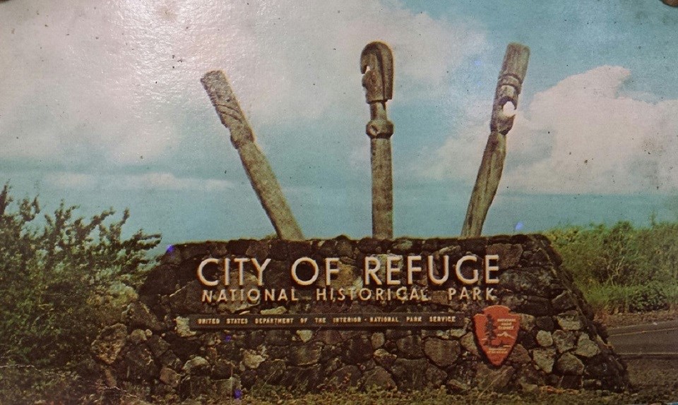 City of Refuge National Historical Park entrance sign with three carved kiʻi