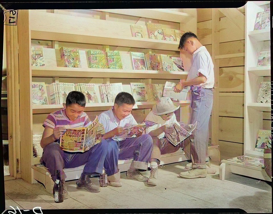 Four little evacuees from Sacramento, California, read comic books in the newstand at this War Relocation Authority center for evacuees of Japanese descent.