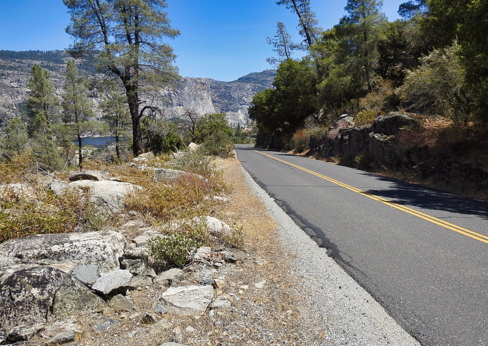 A car on railroad tracks with mountains and trees in background.