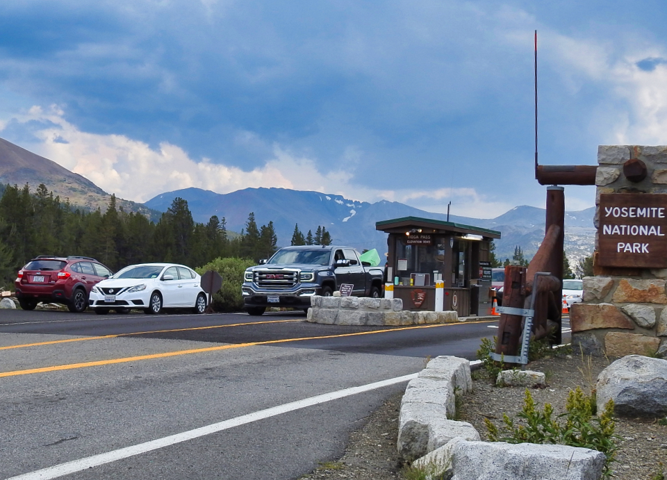 Two people stand next to an older car with two rock towers on either side of the car.