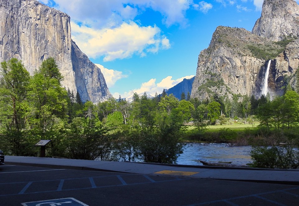 Two women on bank of river with cliffs and a waterfall in background.