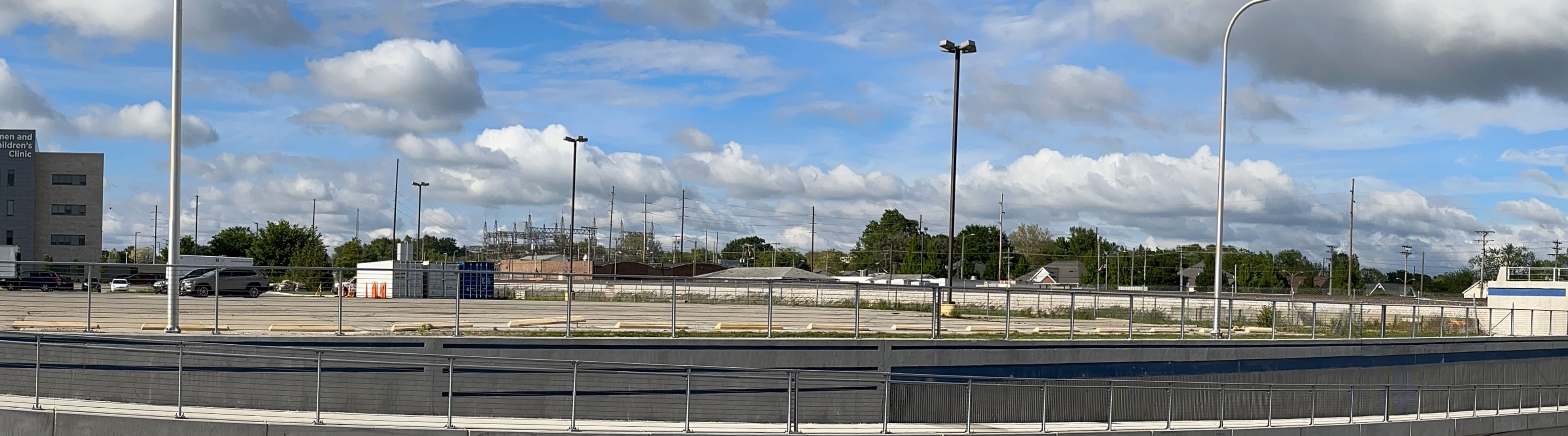 A row of smoldering and charred house frames line a city street. Onlookers and soldiers stand on the sidewalk, looking at the houses.