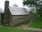 The restored cabin has two stone chimneys, wooden siding, and a shingled roof. 