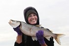 a smiling woman holding a large fish in two hands