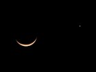 A slight crescent moon is lit from the bottom; a planet nearby is similarly lit.