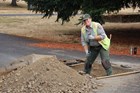 A woman wearing a National Park Service uniform stands in an archaeological excavation unit.