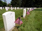 a row of US government-issue gravestones with American flags in front of them.