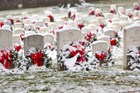 snow covers a line of headstones, each marked with a wreath.