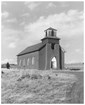 A historic image of a church with a slanted roof and one bellow tower.
