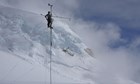 A man climbs a weather station antennae high in the mountains.