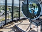 Photograph of lighthouse beacon lens with background view of windows