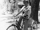 A black and white photo of woman with short hair on a bicycle, smiling