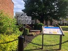 A highway historical marker and wayside exhibit stand on a courthouse grounds.
