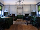 Assembly room of Independence Hall, wooden chairs in a semi-circle and tables with green cloth.