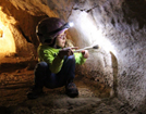 A youth volunteer cleaning lint off of a cave wall.