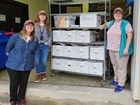 Photo of 3 people standing near a shelf of archival boxes.