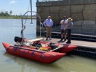 three men stand near a boat