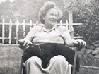 Smiling woman in lawn chair with small black cocker spaniel in her lap.
