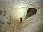 A person standing in a white-coated cave passage.