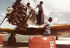 Color photo of three women in denim working on an airplane engine 
