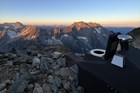 a composting toilet with a view of jagged mountains at sunset