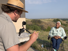 a man in a park ranger uniform interviewing a man with braided hair