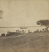 A boat with men standing on a makeshift dock over ruins of a fort in the foreground.