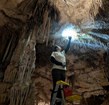 person on ladder cleaning stalactites in cave