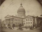 Black and white photo of a large courthouse with a copper domed roof and four square wings.