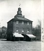 three story square brick building with a tunnel in the middle.