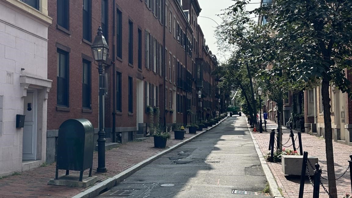 Photo looking down the street with brick buildings, lamposts, and trees lining it