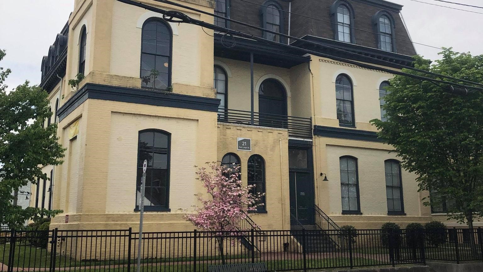 A large yellow brick building on the corner, with a black metal fence surrounding the grounds