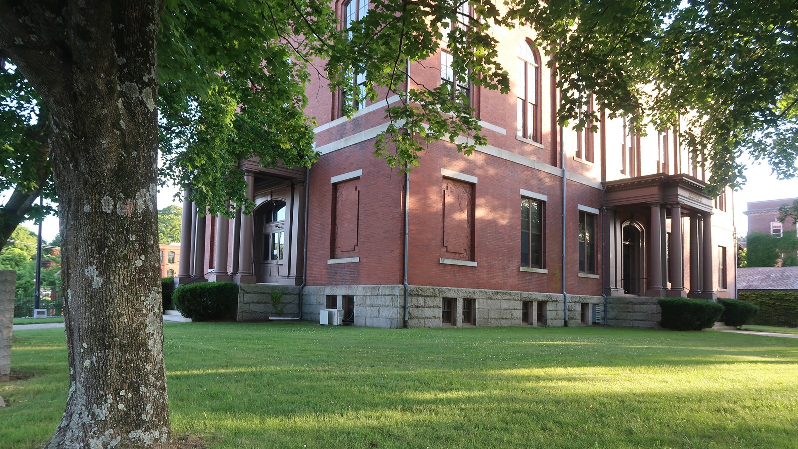 Brick building with tree and grass in foreground.