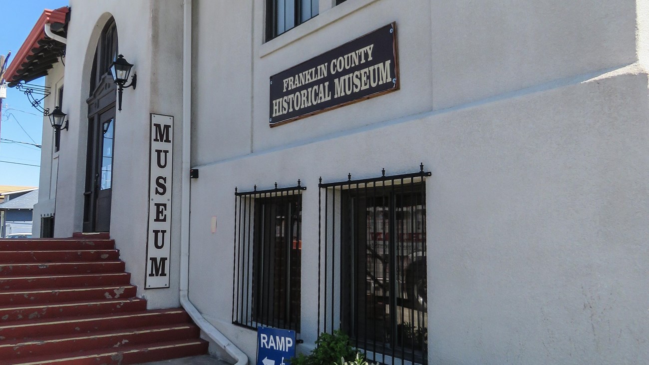 Color photograph of a solid white structure. A sign reads “museum” near the entrance.