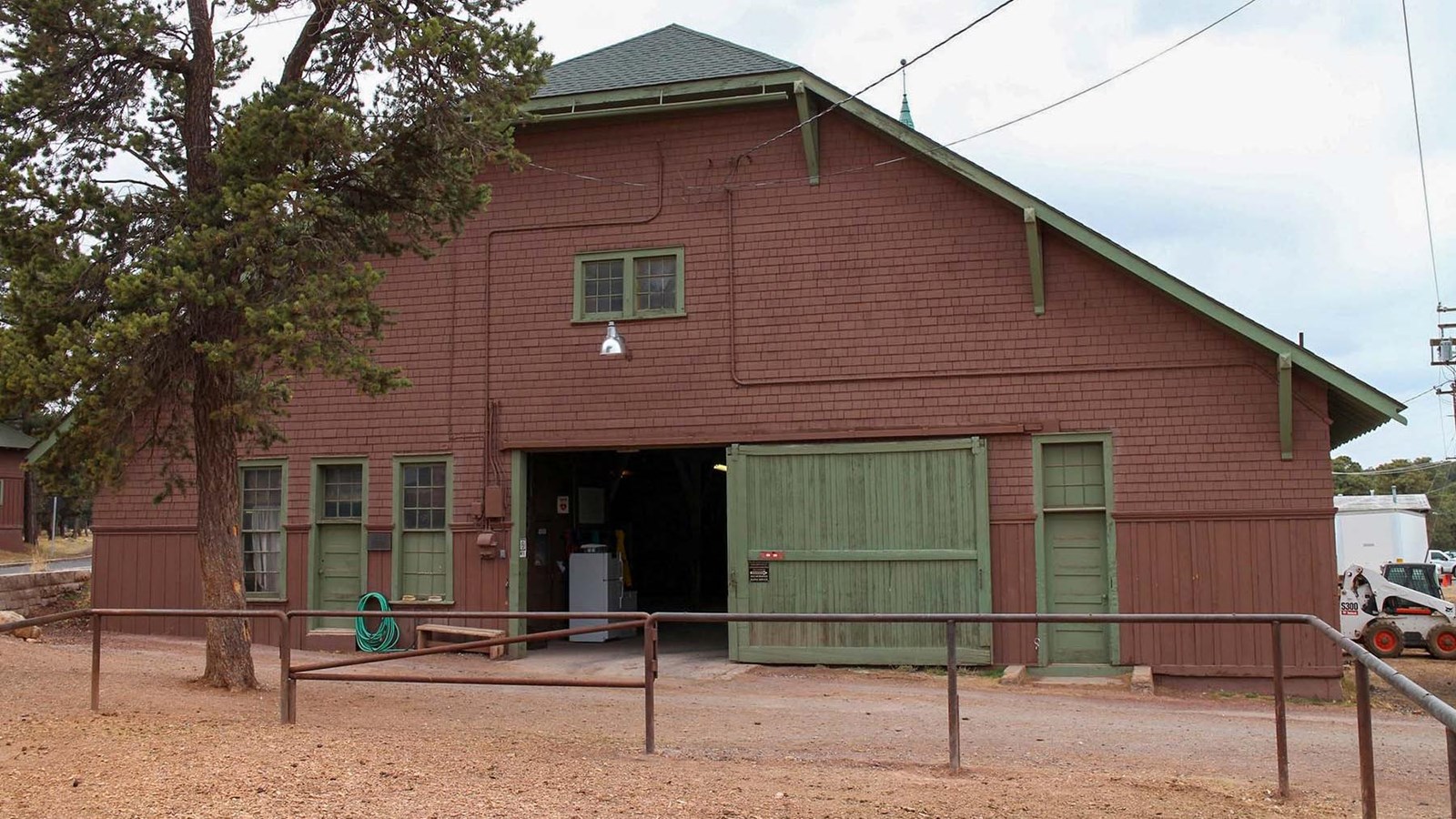 a large brown, wooden  building with a pitched green roof and large sliding front door.