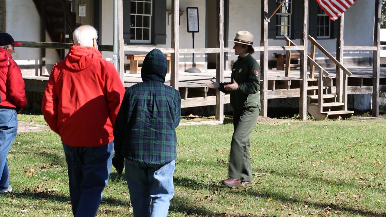 A park ranger speaking to visitors outside of a historic home