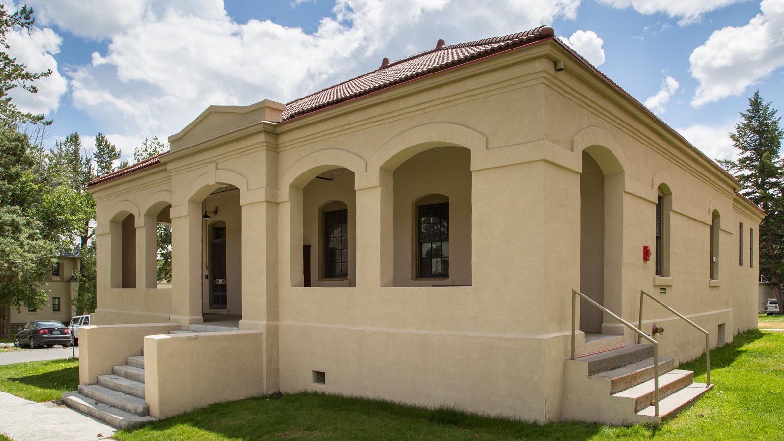 A historic stucco building with red shingles on the roof.