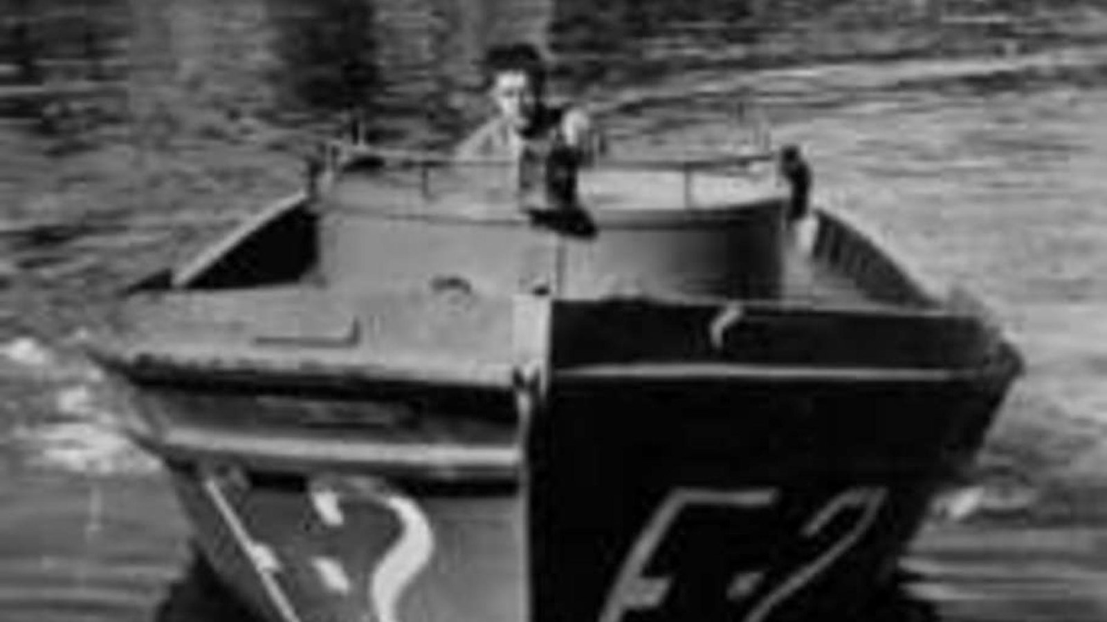  Man operating small mine boat near repair shop.