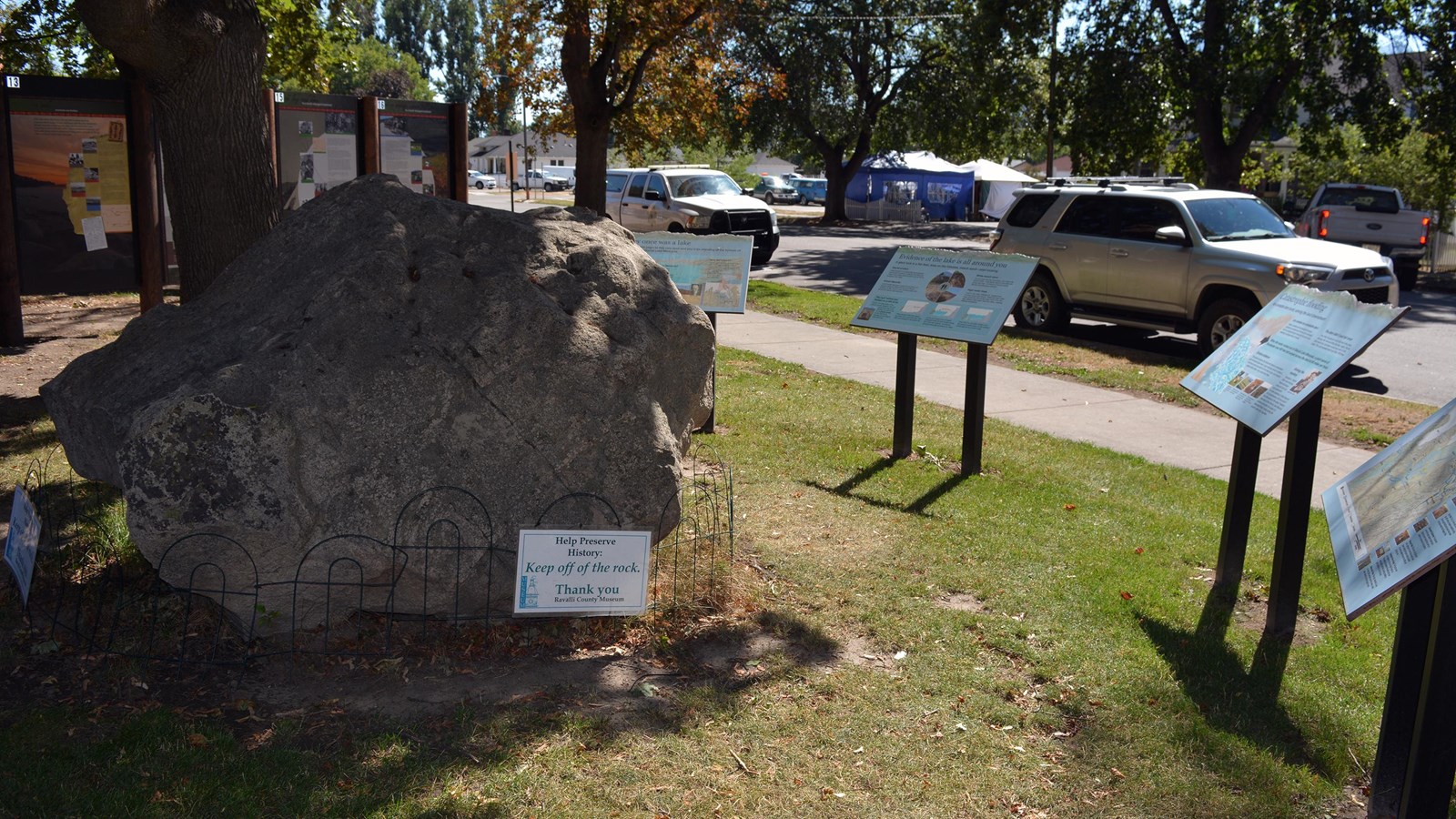 an erratic boulder and several wayside exhibits about floods under a tree outside.