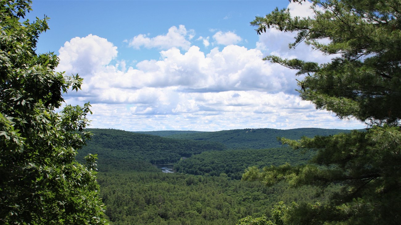 View overlooking lush river valley. Clear river cuts through rolling green tree-covered hills.