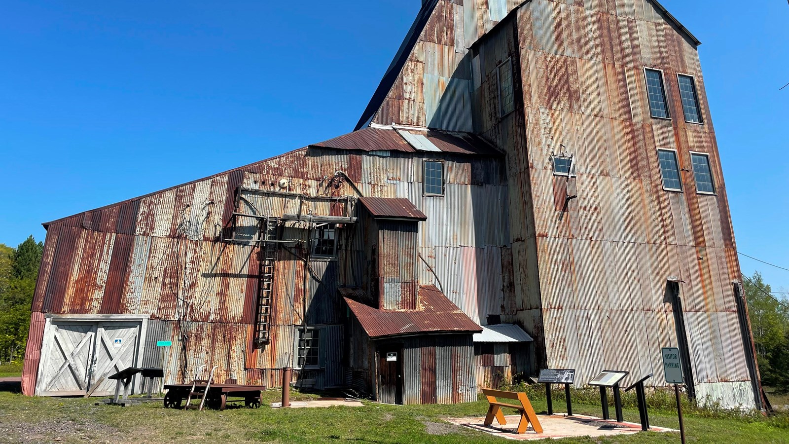 A tall rusty metal industrial building stands before blue skies. 